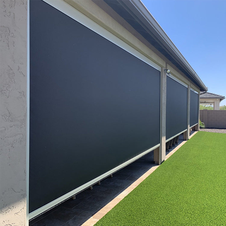 Dark grey zip track outdoor blinds installed along the side of a house with artificial turf